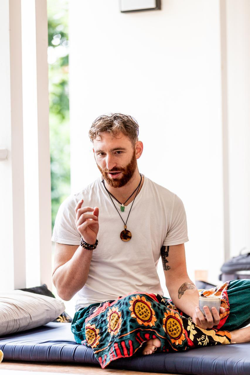 Josh Muller sitting cross-legged in a light-filled studio